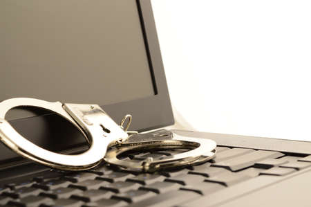 A set of handcuffs and laptop to represent internet police work.の写真素材