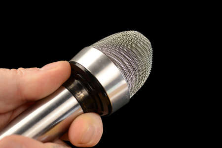 An interviewing reporter using his microphone over a black background.の写真素材