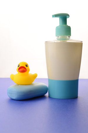 A bar of soap and liquid dispenser over a blue background remind us to wash our hands with a fresh clean feeling.の写真素材