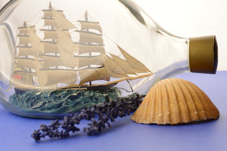 A calming scene of blues and a anutical ship in a bottle with a seashell and lavender.の写真素材