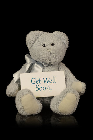 An isolated over black image of a teddy bear with a get well soon message of compassion.の写真素材