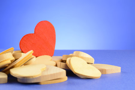A red wood heart shape stands out from the other uncolored pieces.の写真素材