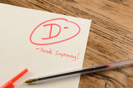 A graded school paper marked in red ink over a wood desktop.の写真素材