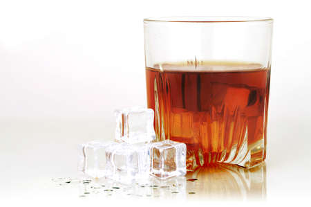 A cold glass of whiskey served with ice and isolated over a clean bright white reflective background.の写真素材