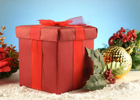A red gift box and bow set inside a festive scene for the Christmas holiday season of gift giving.の写真素材