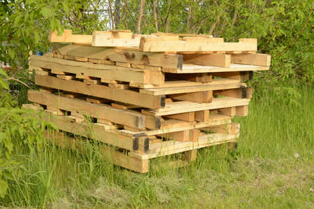A stack of wooden pallets for industrial use are stored outside in the yard.の写真素材