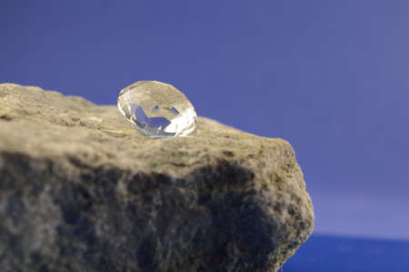 A brilliant cut diamond displayed on top of a rough piece of natural stone.