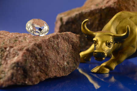 Diamond setting on top of a rough pink quartz rock with a raging gold bull to represent the precious gemstones industry.の写真素材
