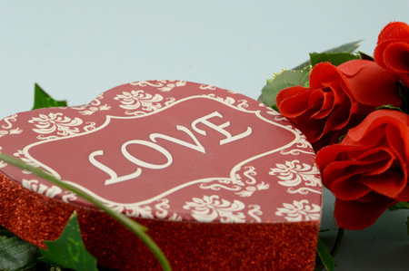A heart shaped box of lovely chocolates next to some red roses for special occassions of romance.の写真素材