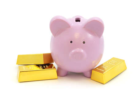 A pink pig coin bank and gold bullion bars over a white background.の写真素材