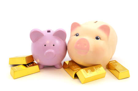 Two pig coin banks and gold bullion bars isolated over a white background for use with financial ideas.の写真素材