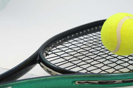 Closeup view of a standard tennis ball and racket of a clean light background.の写真素材