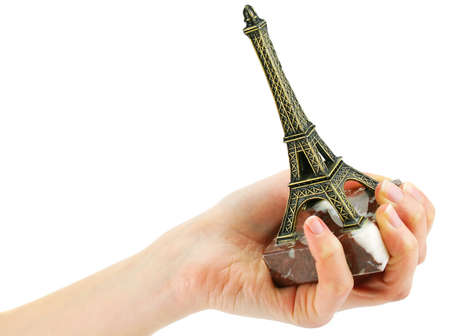 Woman's hand holding statuette of Eiffel Tower isolated on a white backgroundの写真素材