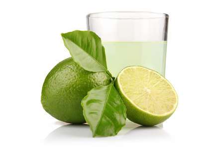 Glass of lime juice and lime fruits with green leaves isolated on whiteの写真素材