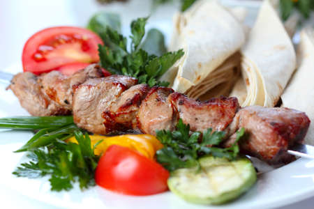 shish pork kebab with greens and vegetables (closeup, selective focus)の写真素材