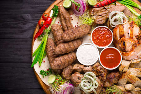 Assorted grilled meat and vegetables on rustic wooden tableの写真素材