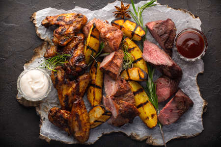 Assorted grilled meat and potatoes on black rustic backgroundの写真素材