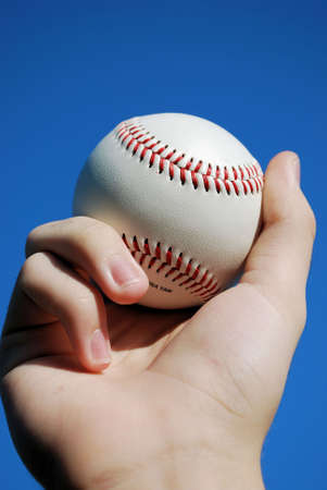Close up view of pitcher holding baseball against blue sky.の写真素材