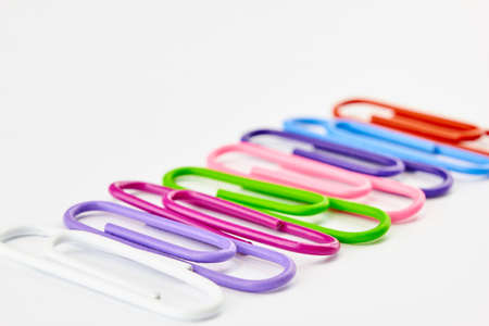 bright paper clips on white background. Pink crimson, blue, purple paperclips memo note and documents staple attach tools illustration. Plastic paperclips backdrop.の写真素材