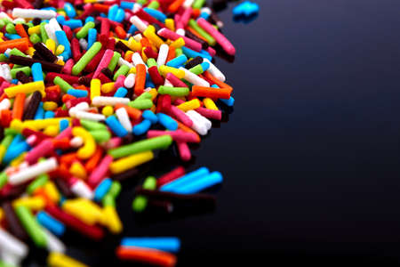 Colorful bright background, multi-colored sticks. Sweet nice candy. Macro shoot photo on black glass...