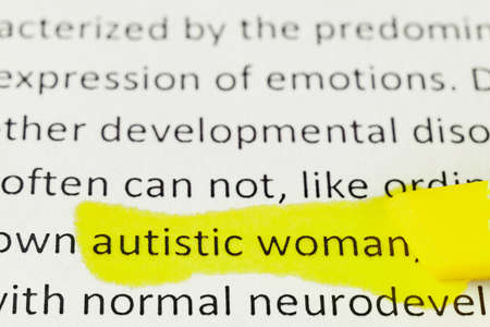 macro photography of the word autism from the newspaper underlined with red and yellow markersの写真素材