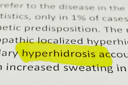 macro photography of the word hyperhidrosis from the newspaper underlined with a red and yellow text separatorの写真素材