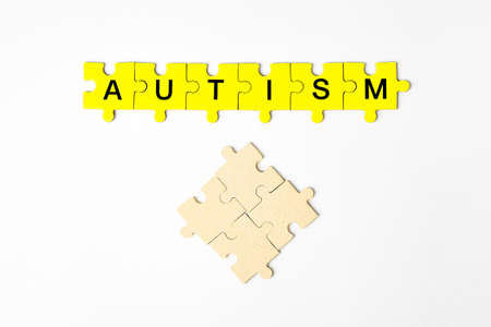 autism, concept the word autism is made up of puzzles in yellow with black letters on a white isolated backgroundの写真素材