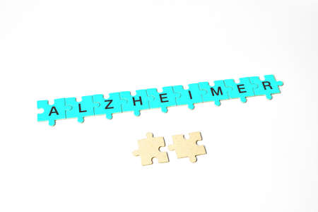 Alzheimer's disease, the word Alzheimer's is composed of puzzles of yellow, blue, with black letters and 2 more puzzles lie below as a concept sign, isolated white backgroundの写真素材