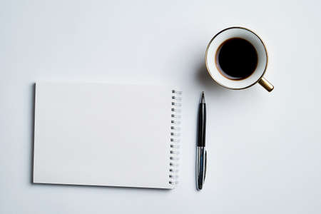 white office Desk with Notepad, pen and coffee Cup, minimalistic design, top view,flat lay,copy spaceの写真素材