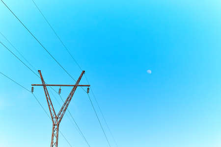 Electric power lines and pylon against blue sky
