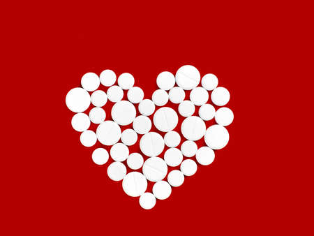 White medicine pills in the shape of a heart on a red background top view with copy space.の写真素材