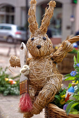 easter decoration, straw easter bunny in a basket with a colorful egg and flowersの写真素材