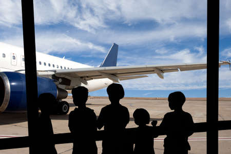Silhouette of people against modern airplaneの写真素材