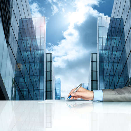 Businessman signing contract against modern officesの写真素材