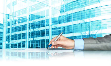 Businessman signing contract against modern officesの写真素材