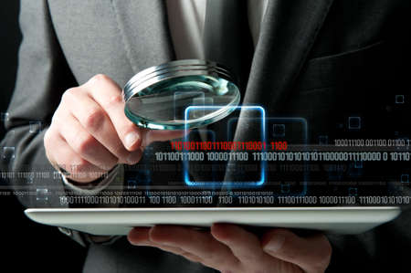 Businessman looks for the malicious code of a virusの写真素材