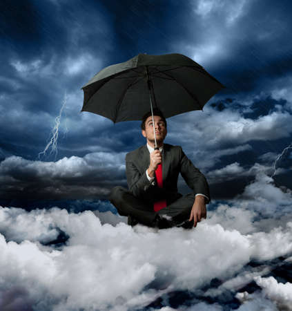 Businessman on a cloud during a stormの写真素材