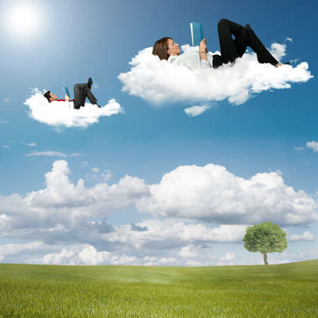 Boy and girl reading book on the cloudsの写真素材