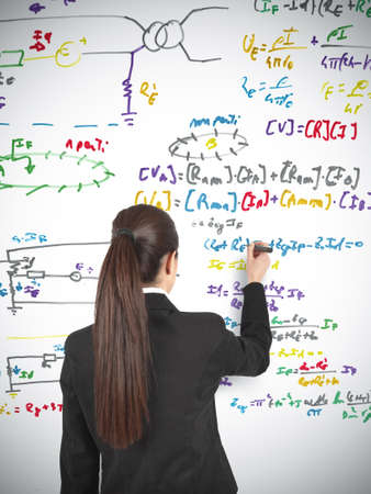 Businesswoman drawing formula in a whiteboardの写真素材