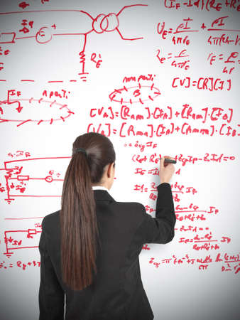 Businesswoman drawing formula in a whiteboardの写真素材