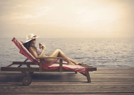 Woman relaxing on a beach during sunsetの写真素材