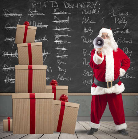 Santa Claus with megaphone with list of gifts delivery in a blackboardの写真素材