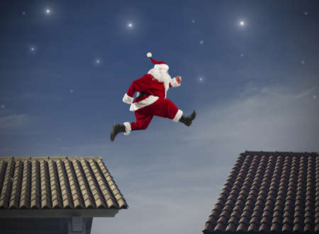 Fast Santa Claus jumping on a roofの写真素材