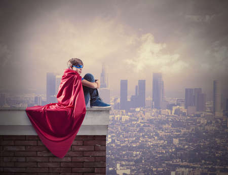Superhero kid sitting on a wall that controls the cityの写真素材