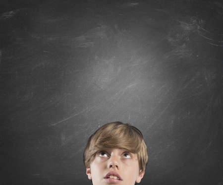 Young boy thinks against a blank wallの写真素材