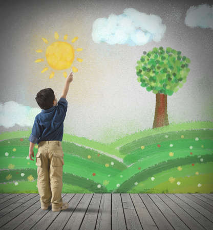 Young child draws a green panorama in a gray wallの写真素材