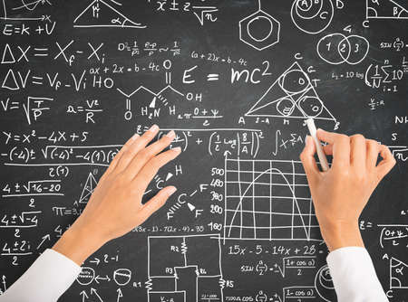 Hand writing science and math formulas on chalkboard