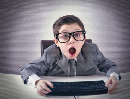 Shocked child nerd working with a computerの写真素材