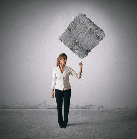 Determinated businesswoman lifting heavy rock with a fingerの写真素材