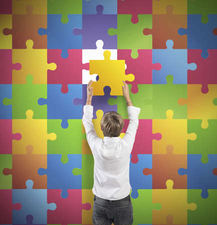 Young boy holds the missing piece of the puzzleの写真素材